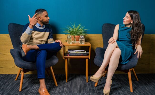 woman wearing dress sitting on chair talking to man