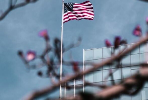 an American flag flying next to a corporate building