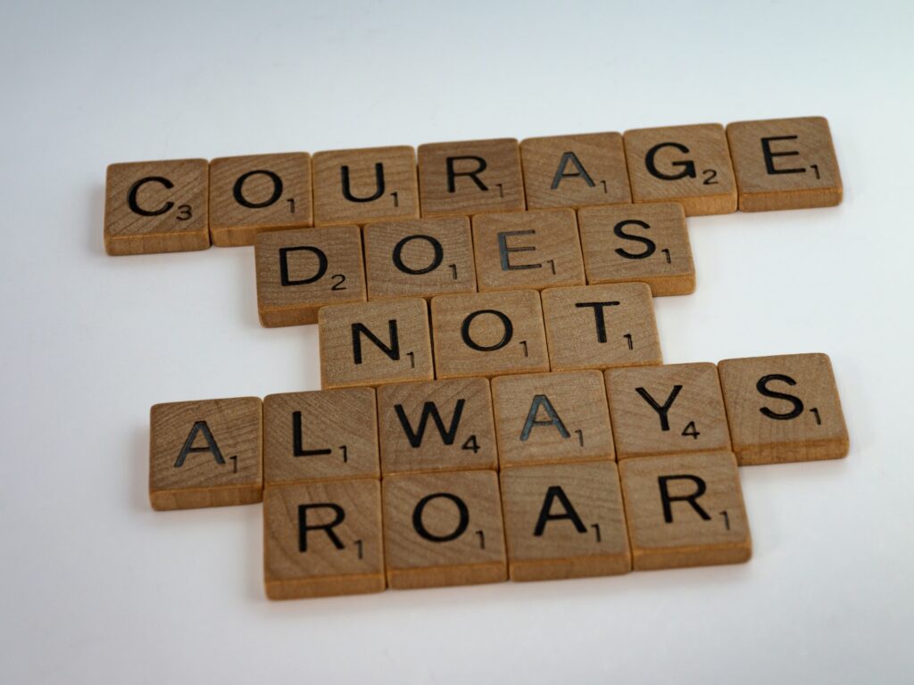 scrabble board game pieces spelling "Courage does not always roar"