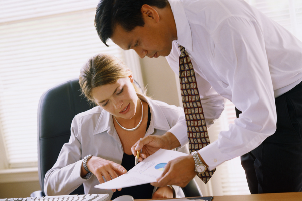 a person showing their coworker a document at their desk