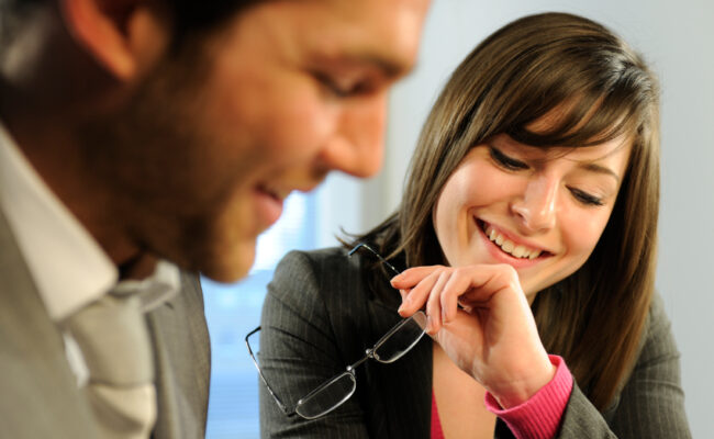 two coworkers smiling and looking at a document together