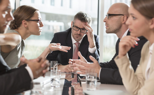 a table full of board members talking and looking stressed