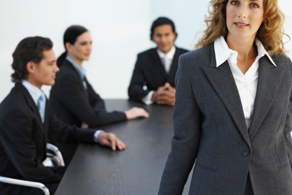 a woman standing at the head of a table in a board room